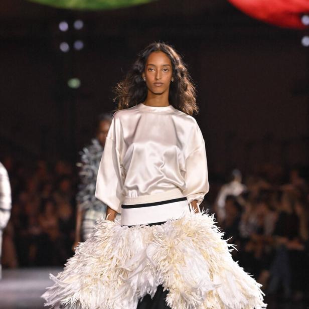 Weißes Satin-„T-Shirt“ zum exzentrischen Rock mit weißen Federn. 