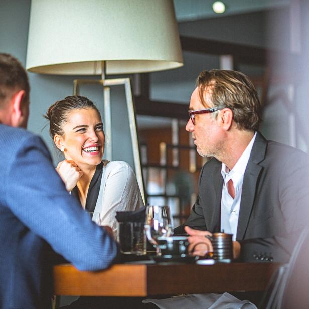 Drei Personen sitzen an einem Tisch in einem Restaurant und unterhalten sich.