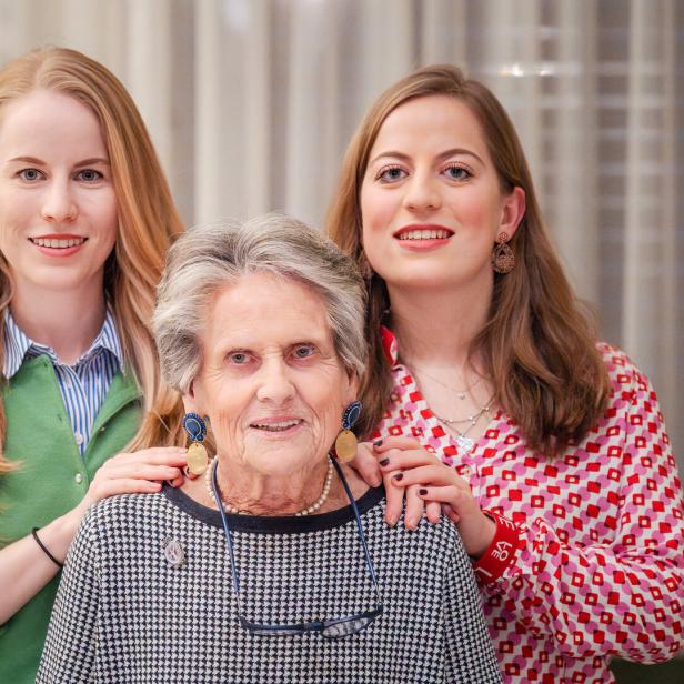 Drei Frauen unterschiedlichen Alters posieren lächelnd für ein Porträt.