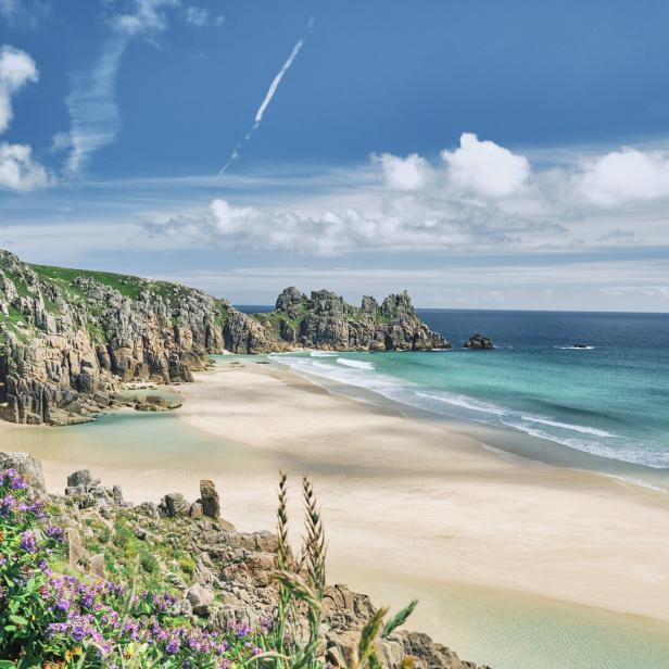 Scenic views across Pedn Vounder Beach towards Logan's Rock, Cornwall on a sunny June day.