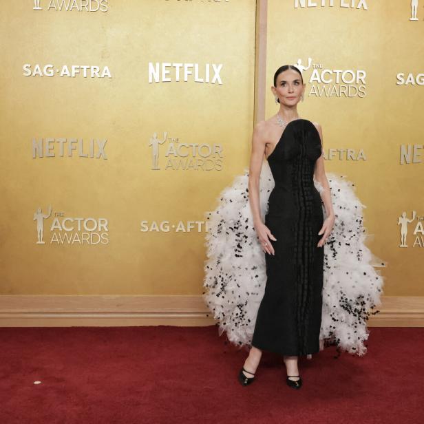 Demi Moore in einem schwarzen Kleid mit Federn auf dem roten Teppich.