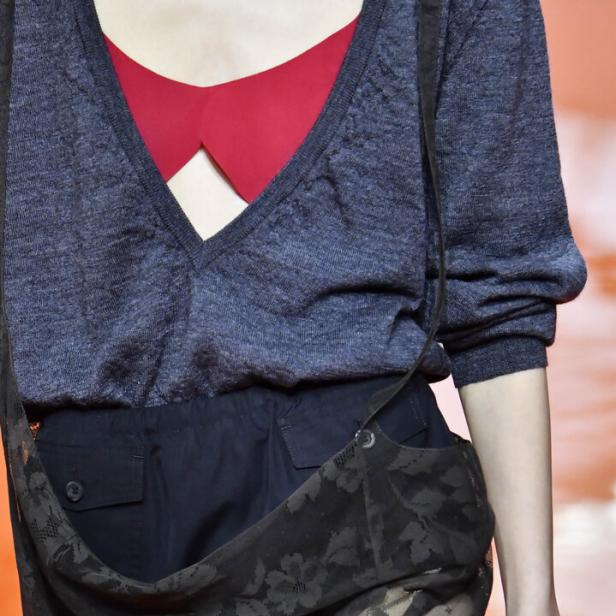 Eine Frau mit einem roten BH, und einer blauen offenen Bluse und einem schwarzen Spitzentuch um die Hüfte