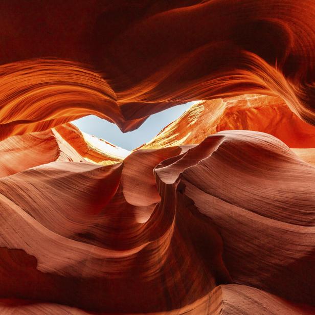 Rote, geschwungene Sandsteinformationen mit einem schmalen Blick auf den blauen Himmel in der Mitte.