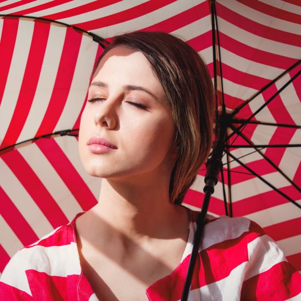 Portrait of a young woman in striped jacket and umbrella.