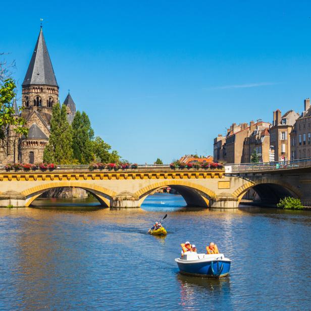 Cityscape of Metz with Temple Neuf (new temple), Moyen Bridge and Moselle River with boats and kayak in Metz, France
