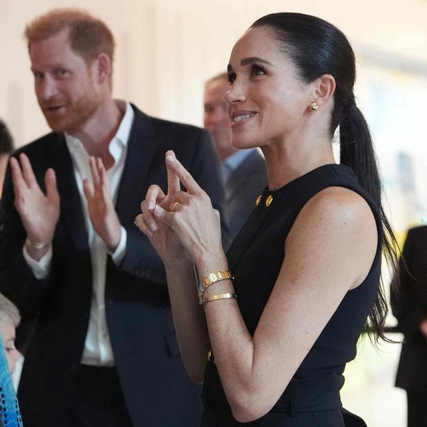 Meghan bei einem Besuch in Melbourne im Gespräch mit Gästen, dahinter Harry